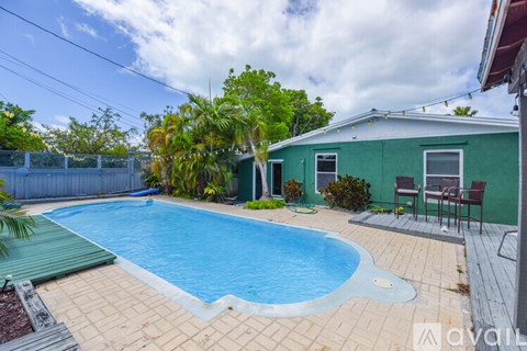 A small pool in a backyard with a green house.