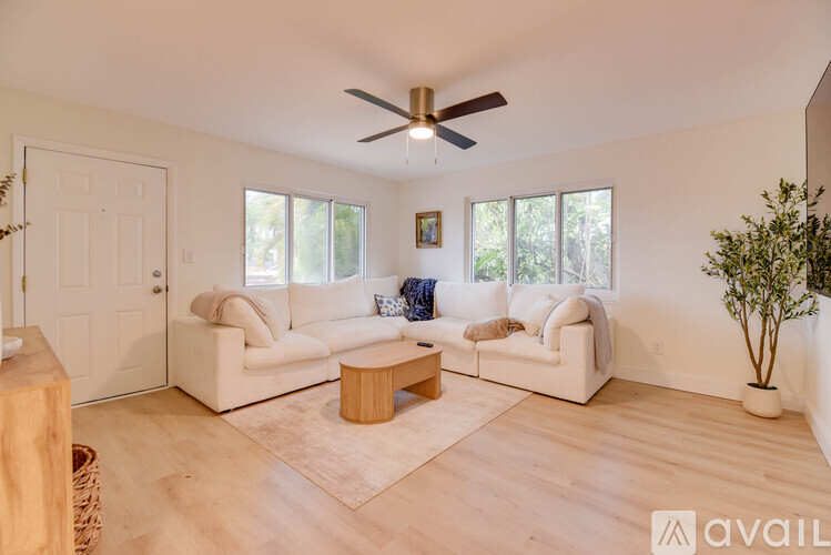 A living room with a white couch, a wooden coffee table, and a ceiling fan.