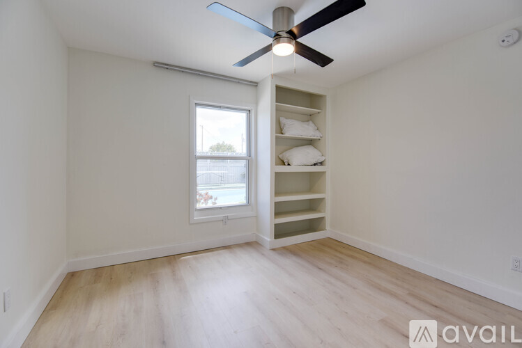 A room with a ceiling fan and a window with a view of a building outside.