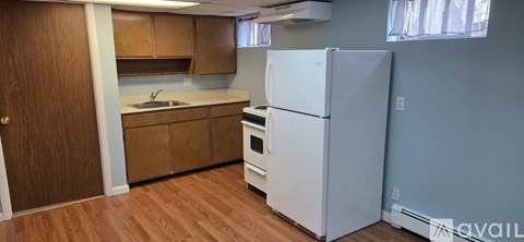 A kitchen with a white refrigerator and wooden cabinets.