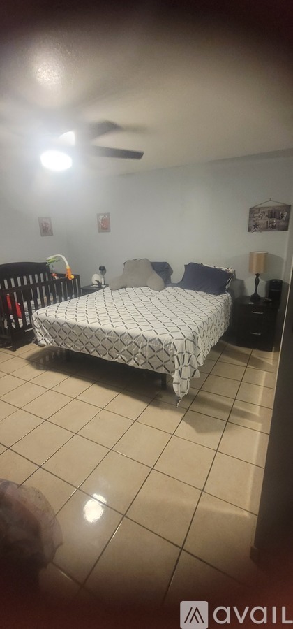 A bedroom with a bed, a fan, and a nightstand.