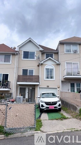 A car is parked in front of a two-story apartment building.