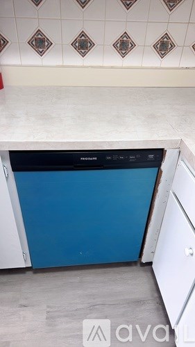A kitchen with a blue dishwasher and white cabinets.