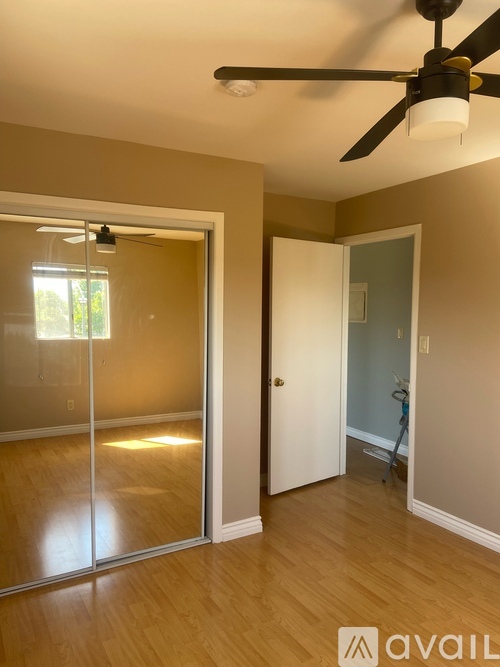 A room with a ceiling fan and a glass door leading to a balcony.