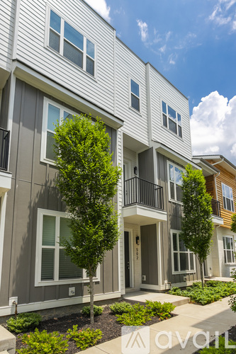 A row of modern townhouses with balconies and trees in front.