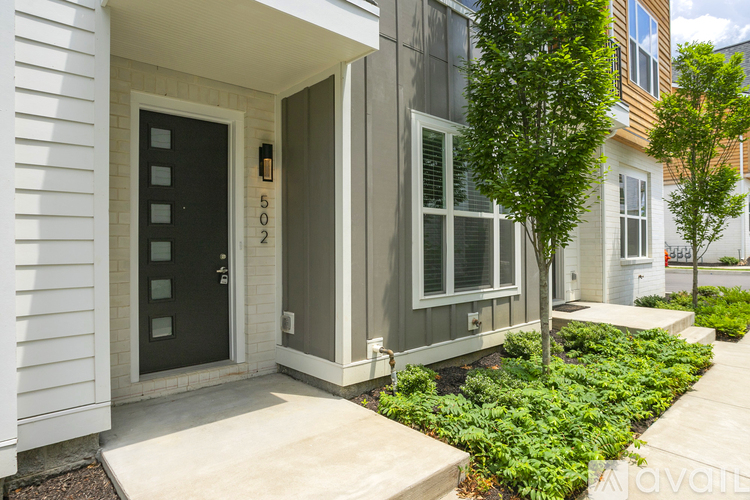 A modern house with a black door and a tree in front.