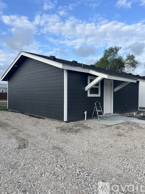 A small house with a grey roof and a white door is under construction.