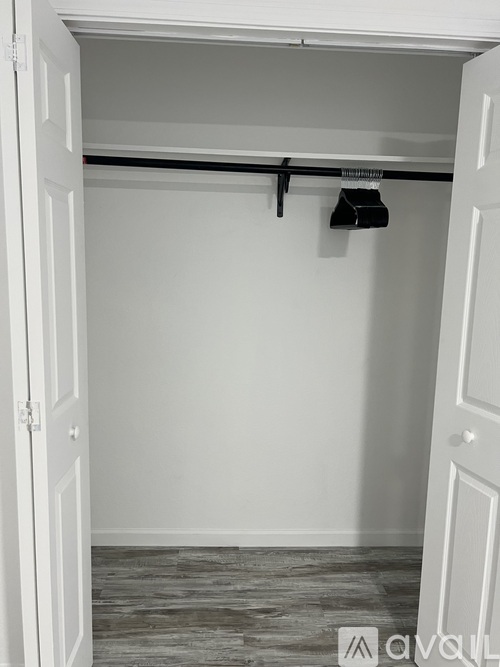 A white door is open to a room with a black coat hanging on a hook.