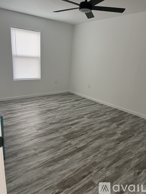 A room with a ceiling fan and a window with blinds.