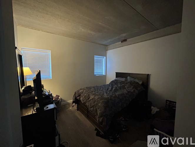 A bedroom with a bed, dresser, and window.