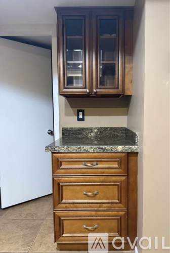 A kitchen with a marble countertop and wooden cabinets.