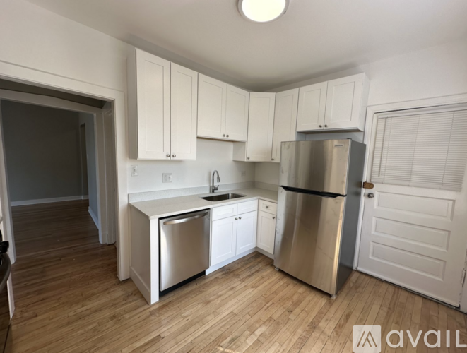 A kitchen with white cabinets and a stainless steel refrigerator.