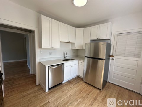 A kitchen with white cabinets and a stainless steel refrigerator.