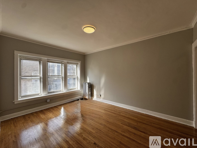 A room with wooden floors and a window overlooking a cityscape.