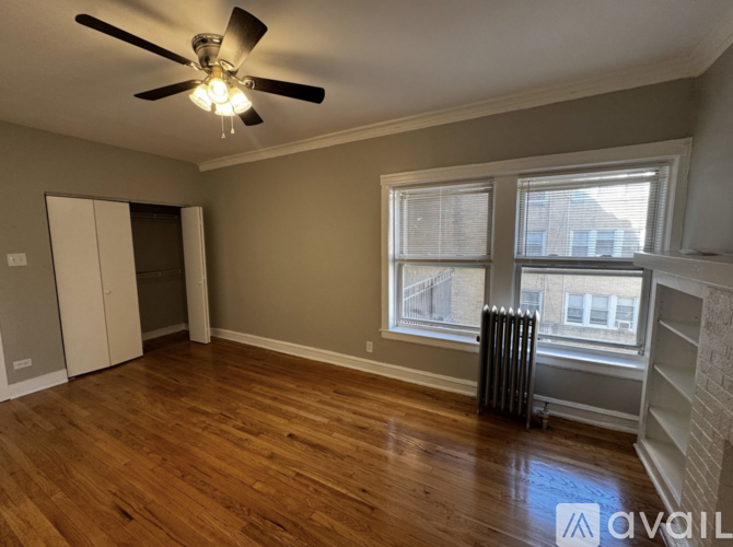 A room with a ceiling fan and a window with a view of a building outside.