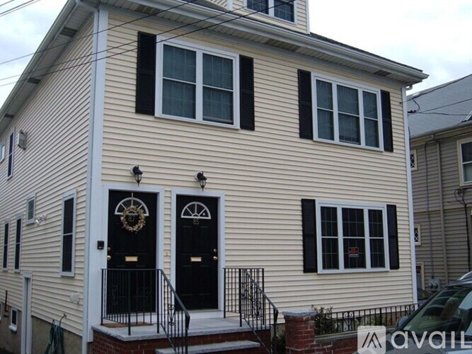 A two-story house with a black front door and a balcony.