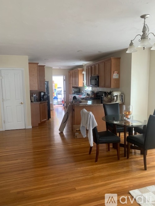 A kitchen with wooden floors and a dining table with chairs.