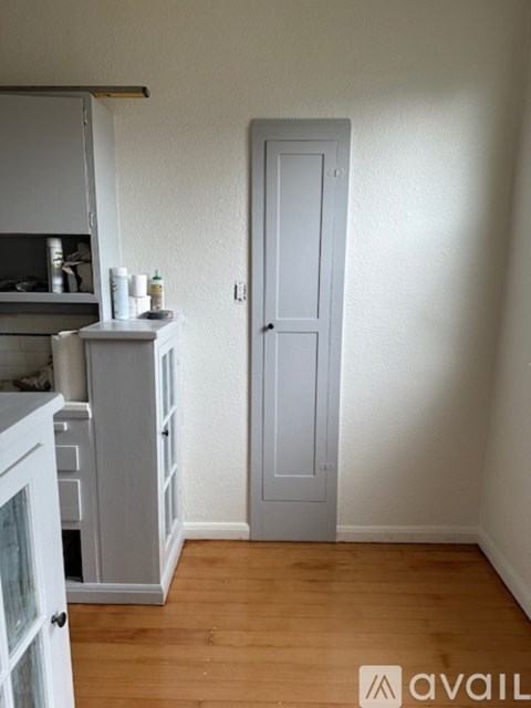 A kitchen with white cabinets and a white door.