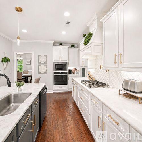 A modern kitchen with white cabinets and a wooden floor.