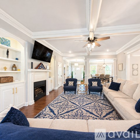A living room with a white couch and a blue rug.
