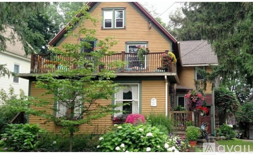 A house with a balcony and a garden in front.