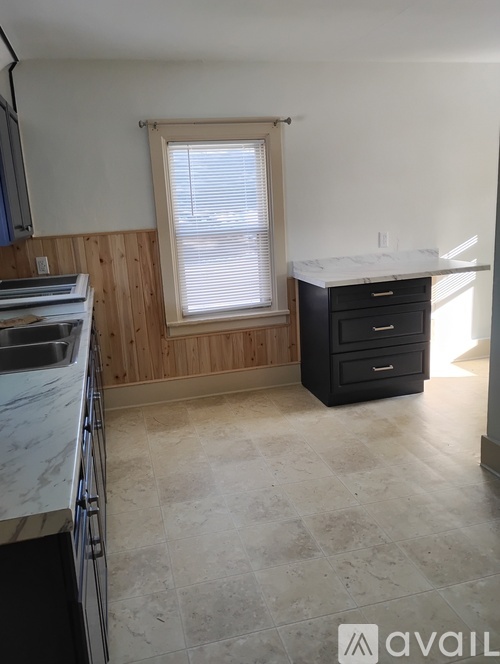 A kitchen with a sink, window, and wooden walls.
