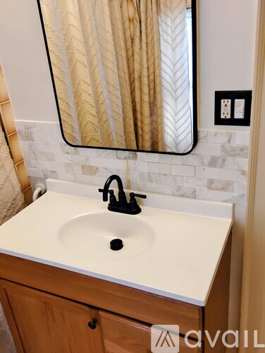 A bathroom sink with a wooden cabinet and a mirror above it.