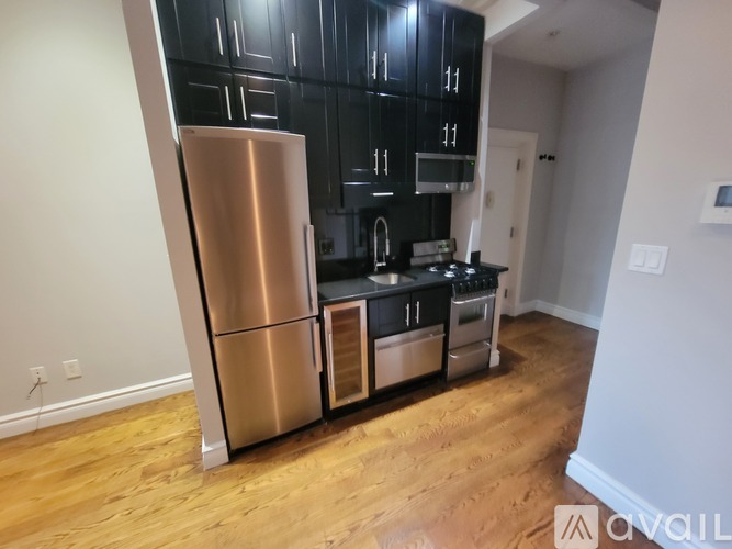 A kitchen with a stainless steel refrigerator and black cabinets.