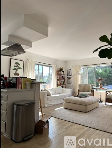 A living room with a white couch and a grey trash can.