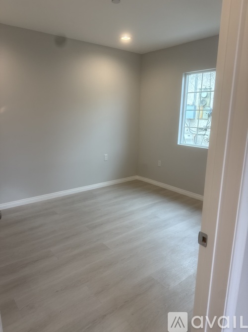 A room with light grey walls and a window with a white frame.