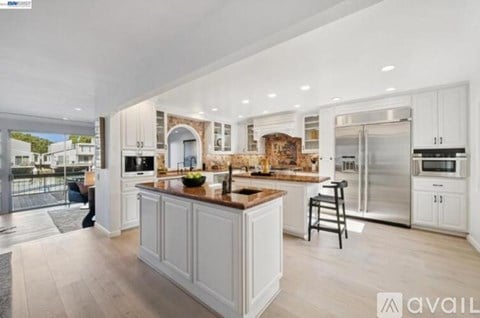 A modern kitchen with white cabinets and a wooden island.