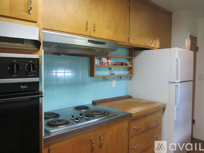 A kitchen with a black stove top oven and a white refrigerator.