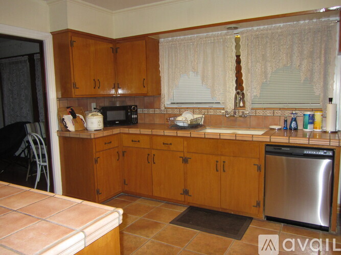 A kitchen with wooden cabinets and a stainless steel dishwasher.