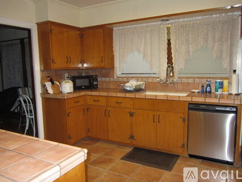 A kitchen with wooden cabinets and a stainless steel dishwasher.