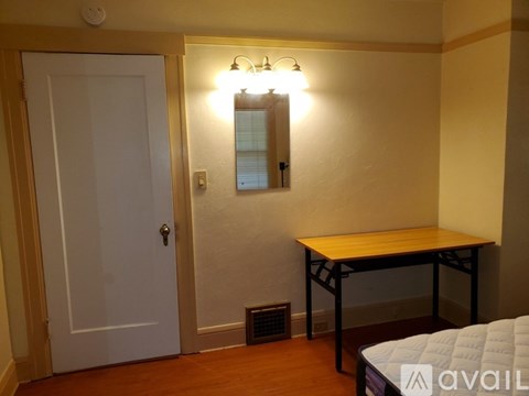 A bedroom with a bed, table, and mirror.