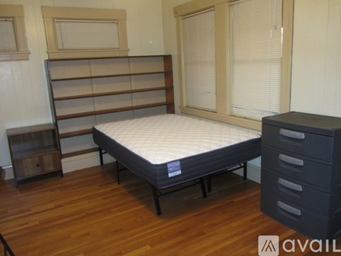 A bed with a mattress and a wooden nightstand in a room.