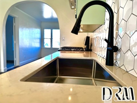A kitchen with a sink and a black faucet.