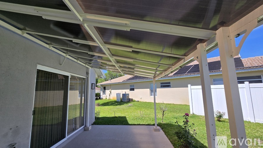 A patio with a white pergola and a concrete floor.