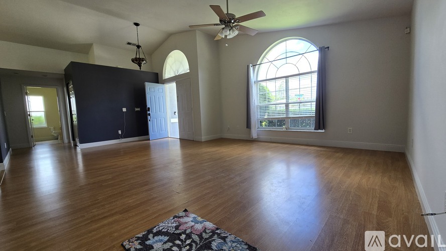 A spacious room with a ceiling fan and a large window.
