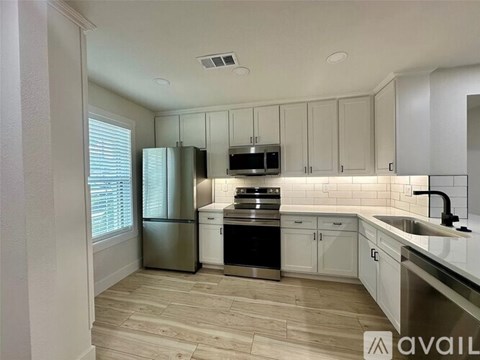 A kitchen with white cabinets and a wooden floor.
