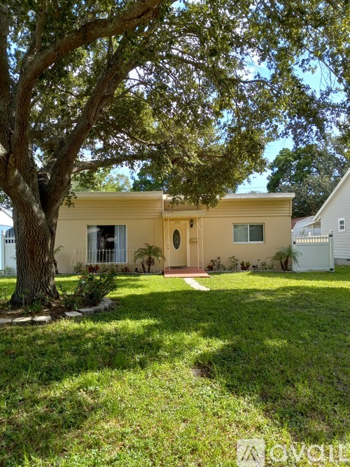 A yellow house with a tree in front of it.