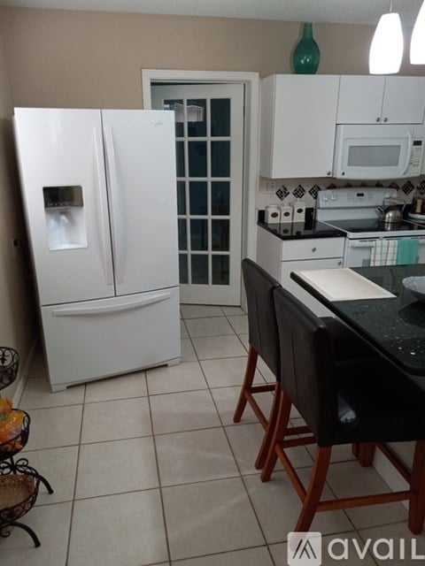 A kitchen with a white fridge and black countertop.