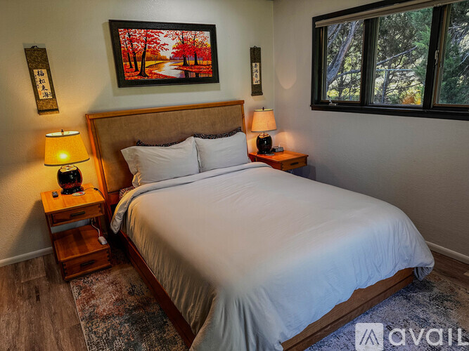A bedroom with a large bed and a painting on the wall.