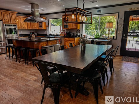 A kitchen with a table and chairs in the foreground and a window in the background.