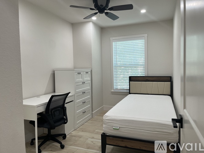 A bedroom with a bed, desk, and chair.