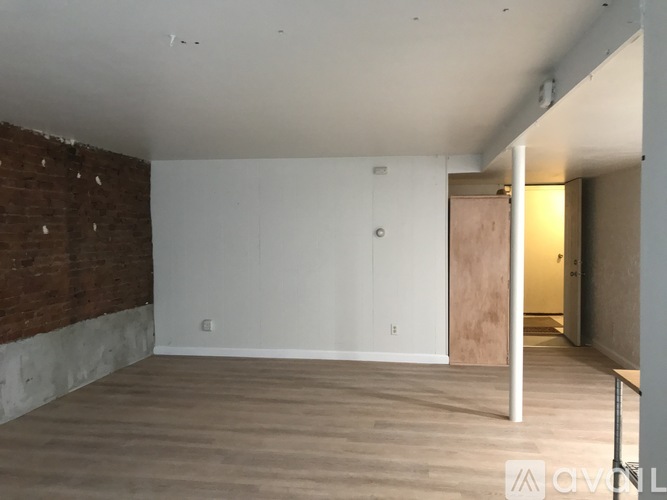 A room with a white ceiling, a brick wall, and a wooden door.