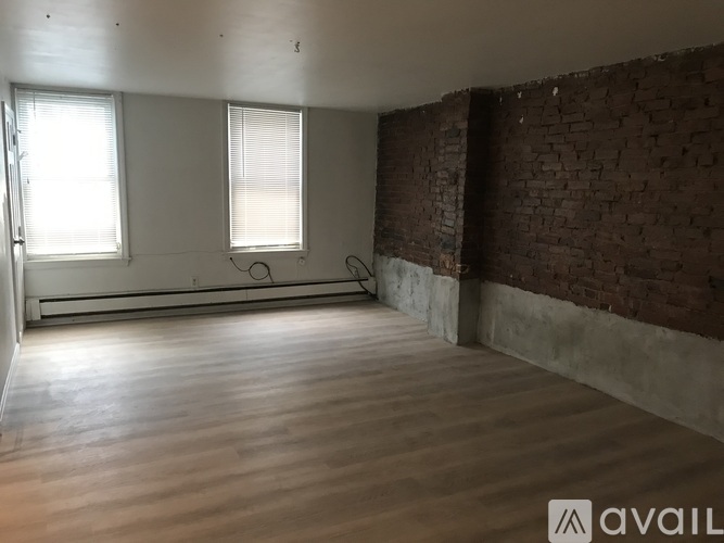 A room with wooden floors and a brick wall.