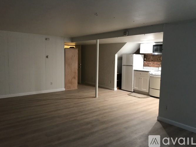 A room with wooden flooring and a doorway leading to another room.