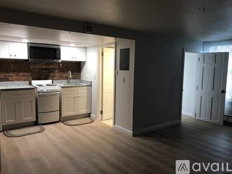A kitchen with a brick wall and wooden floors.