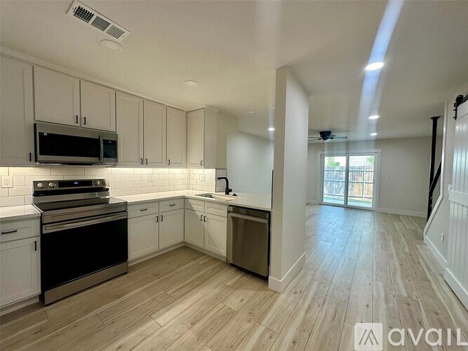 A kitchen with white cabinets and a wooden floor.